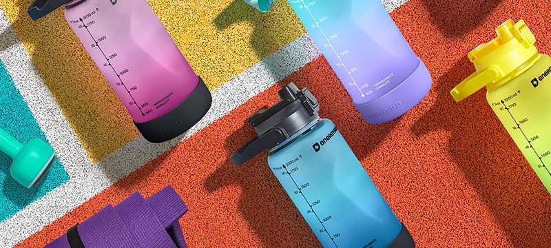EnergyBud half gallon bottles in pink, violet, lime and blue laid out on the same running track